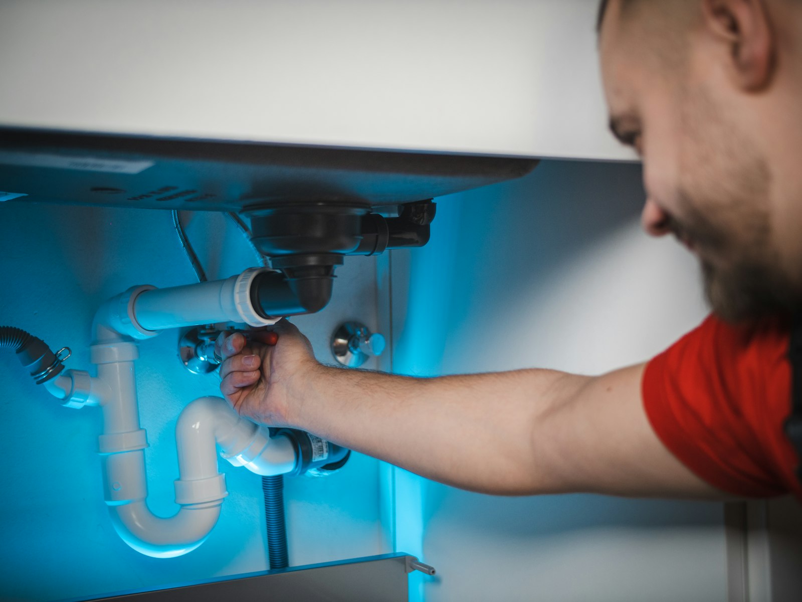 Plumber working on a sink waste pipe under a basin